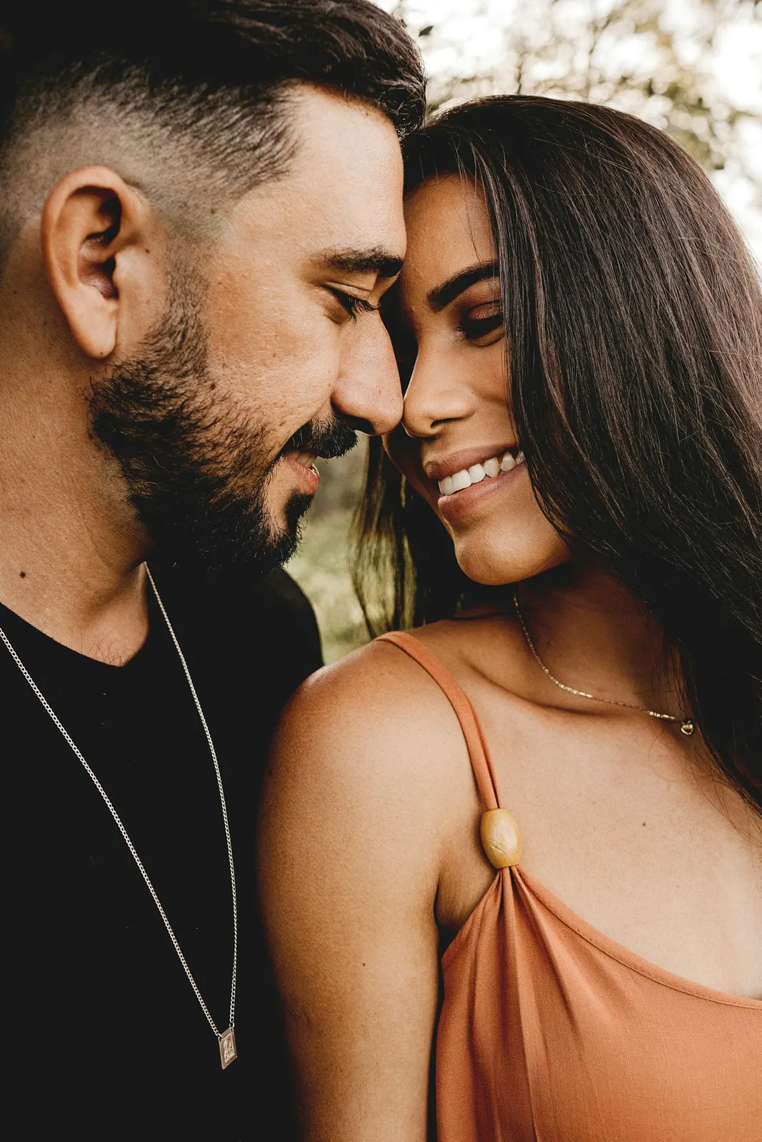 Pareja latina frente con frente, sonriendo con complicidad